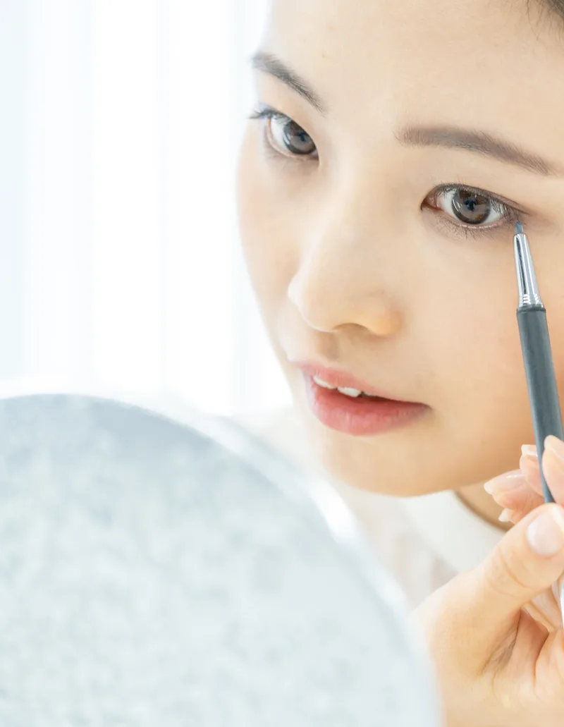 眉ペンシルで眉を描く女性